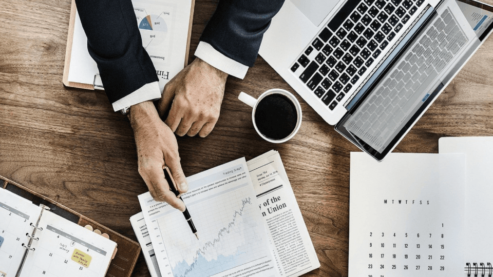 Laptop, cup of coffee and man in suit showing graphs